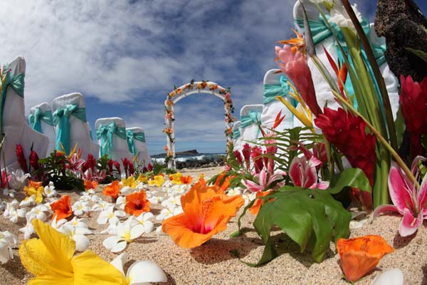 white trellis on the beach with hawaiian flowers on the sand at a ceremony in Hawaii